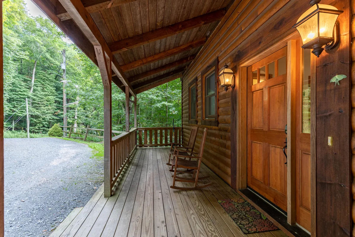 An inviting porch with classic rocking chairs, a rustic wooden door, exterior lanterns, and charming wooden railings. The scene hints at moments of relaxation, conversation, and soaking up the serene mountain surroundings—perfect for stargazing or enjoying fresh air.