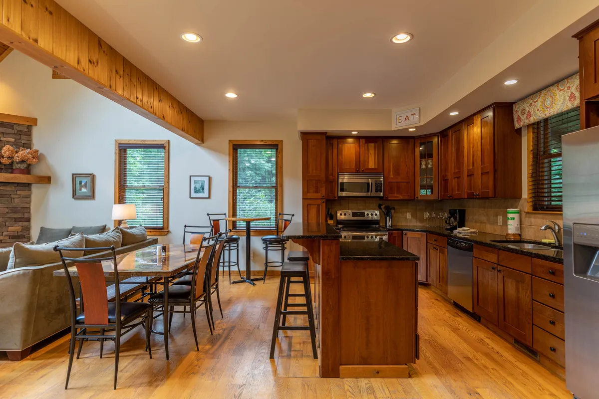 A warm, open-concept kitchen and dining space featuring a kitchen island, dining table, and comfortable sofa, with ample room for cooking, dining, and socializing. The scene highlights the communal aspect of family gatherings after a day outside.